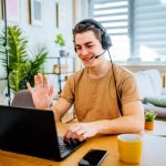 Young man with a headset working on laptop at home